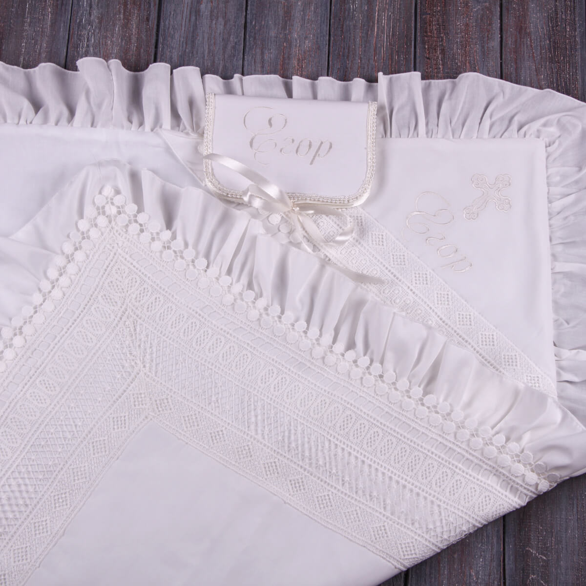 Ivory baptism blanket with a brand label on a wooden surface
