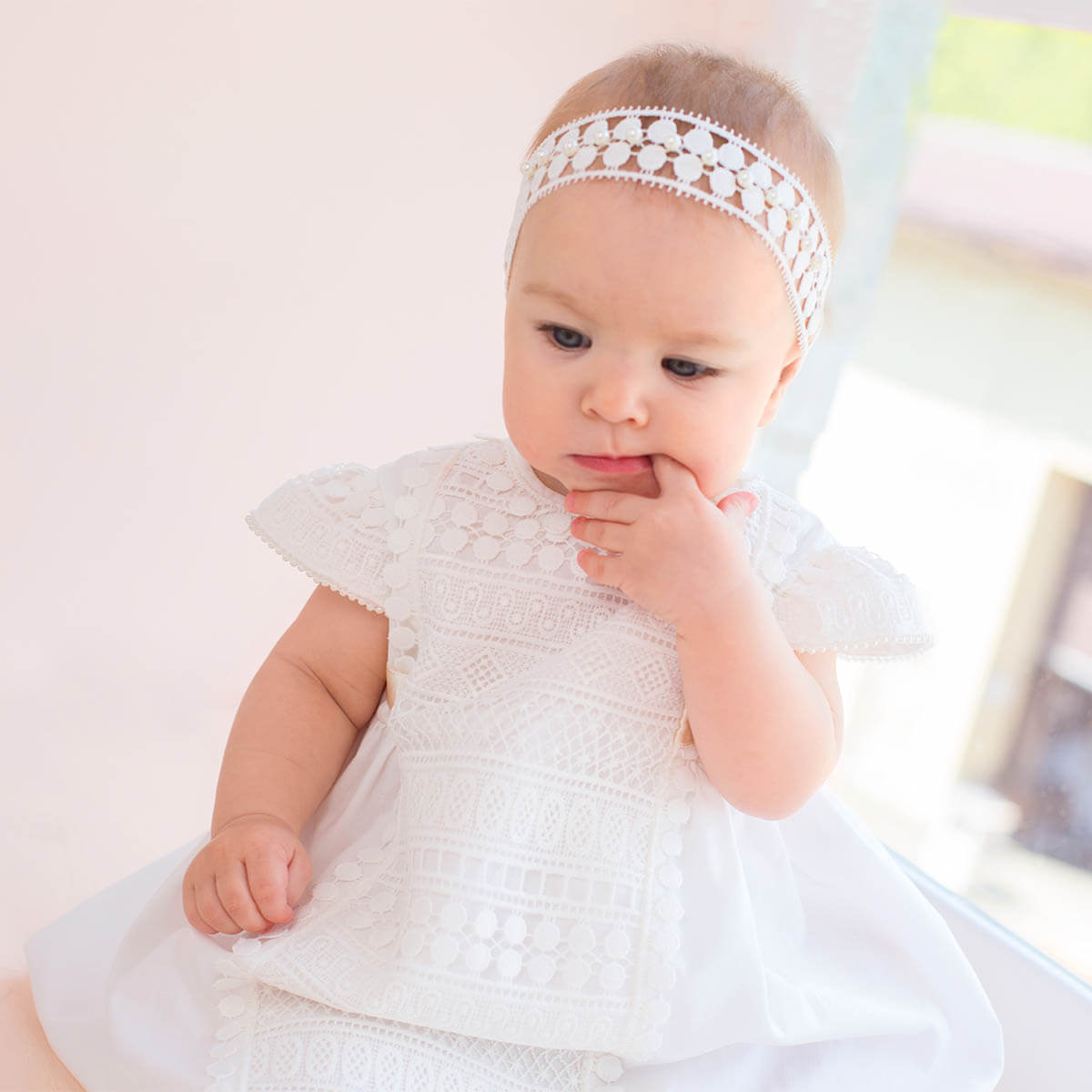 Baptism Dress with Macramé Lace with a lace headband sitting on a light surface.