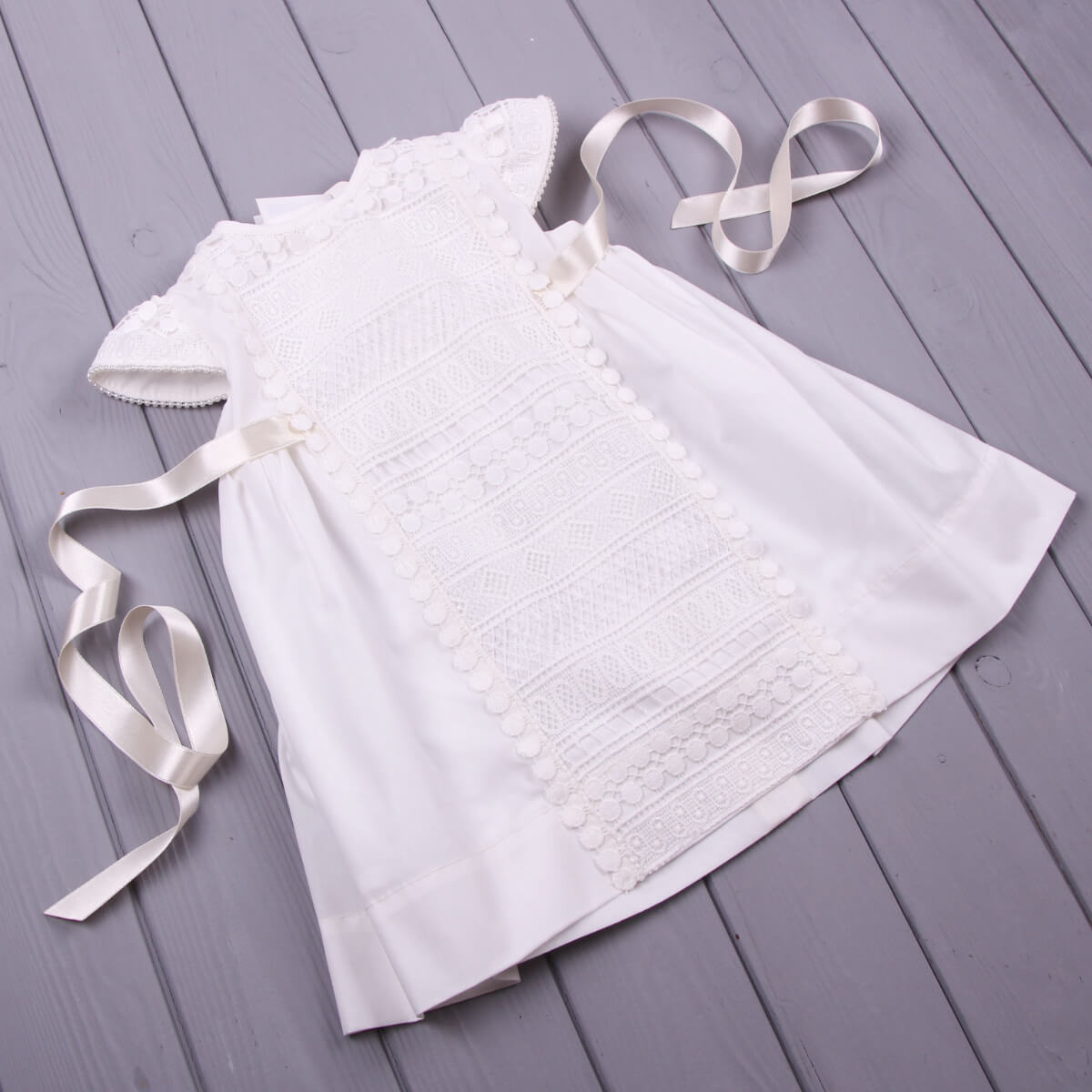 Baptism Dress with Macramé Lace on a gray wooden surface
