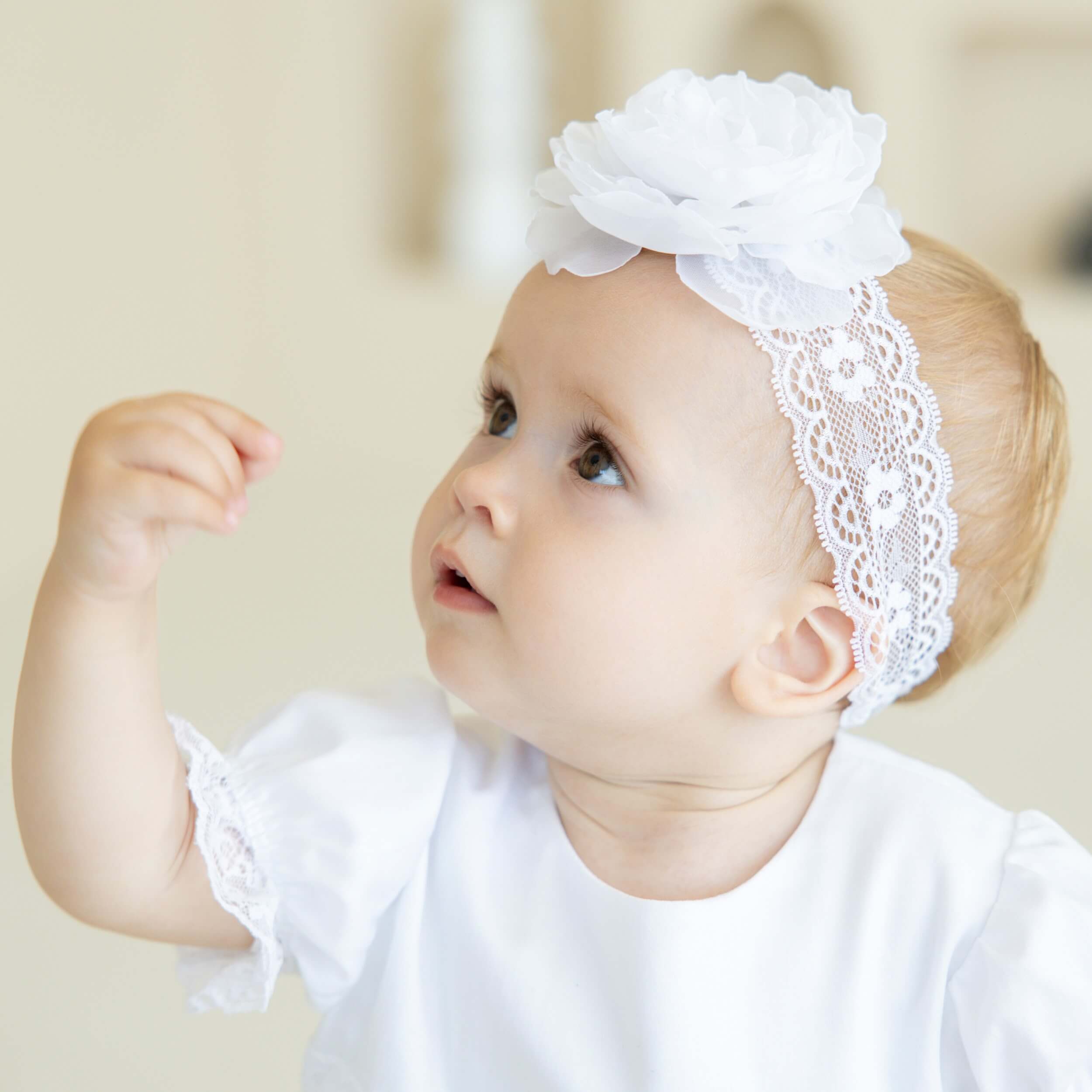 Baby wearing baby headband with a flower on a neutral background
