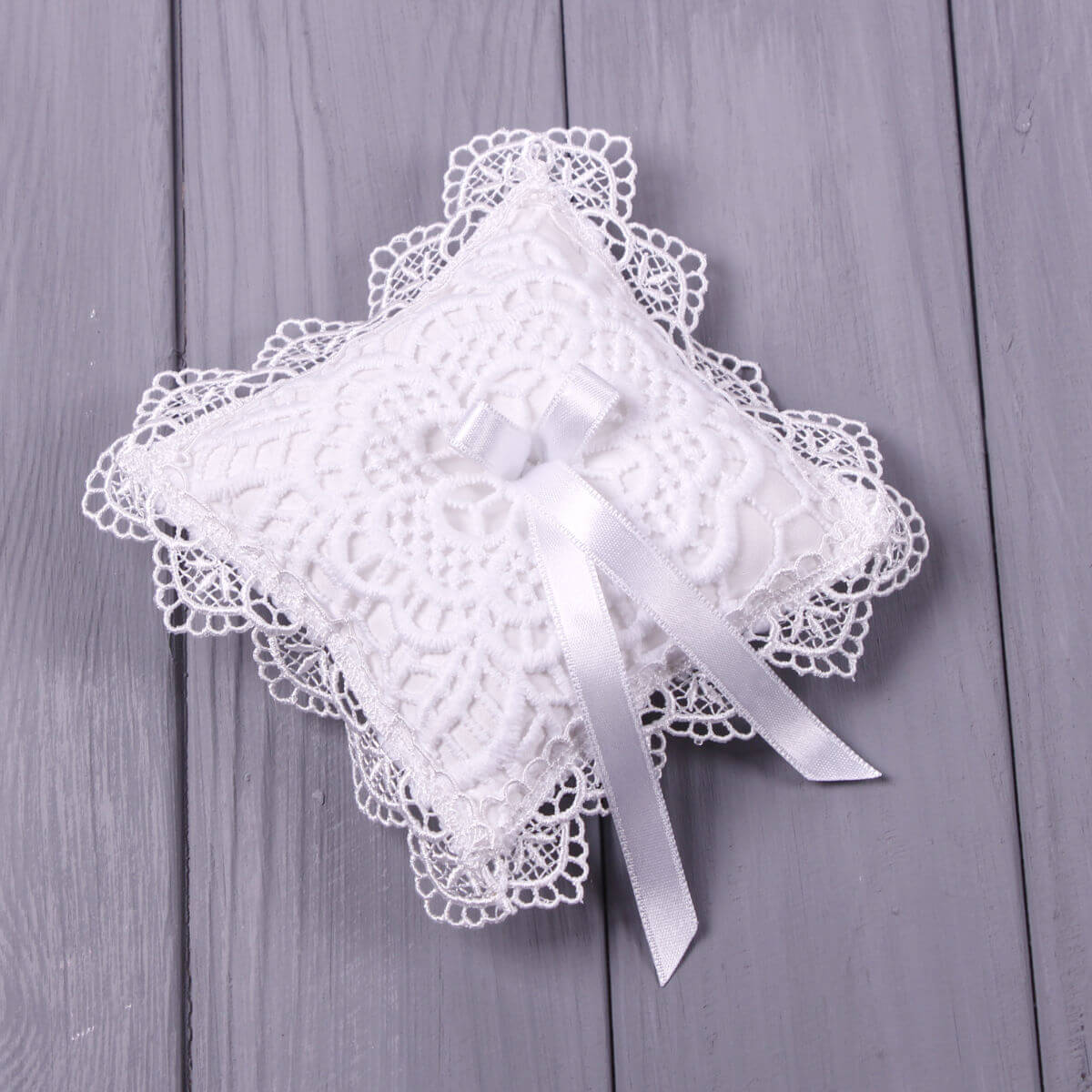 Christening Cross Pillow with a ribbon on a wooden surface