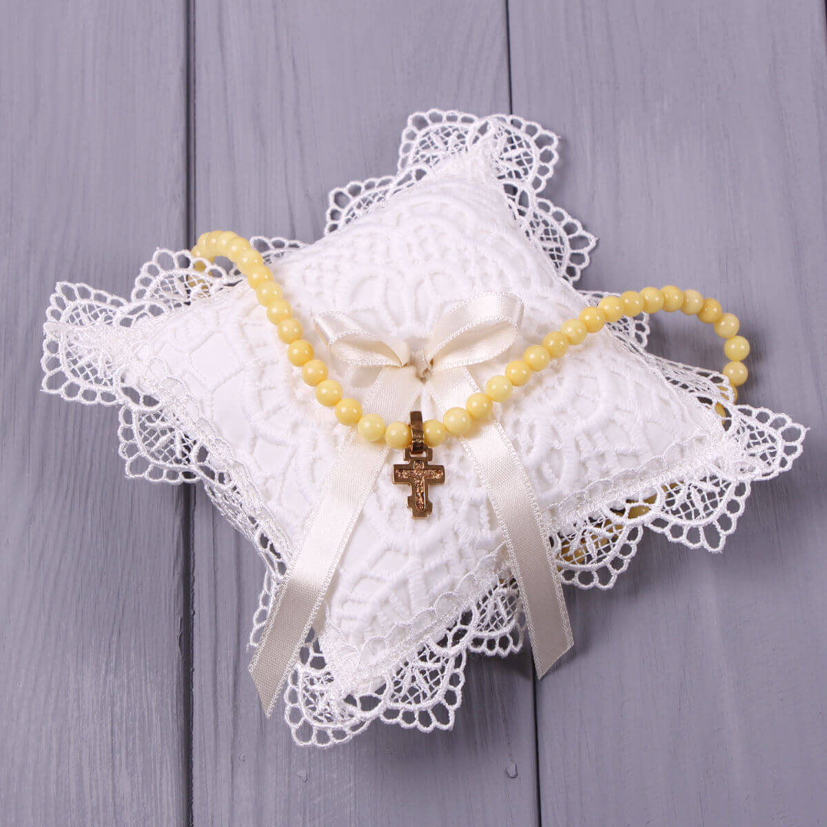 Christening Cross Pillowand a cross pendant on a gray wooden background
