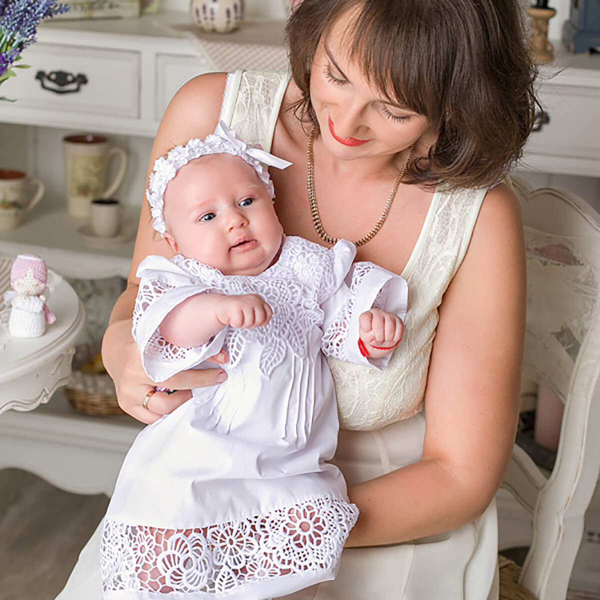 Woman holding a baby dressed in a Baptism Gown for Baby Girl t in a home setting.