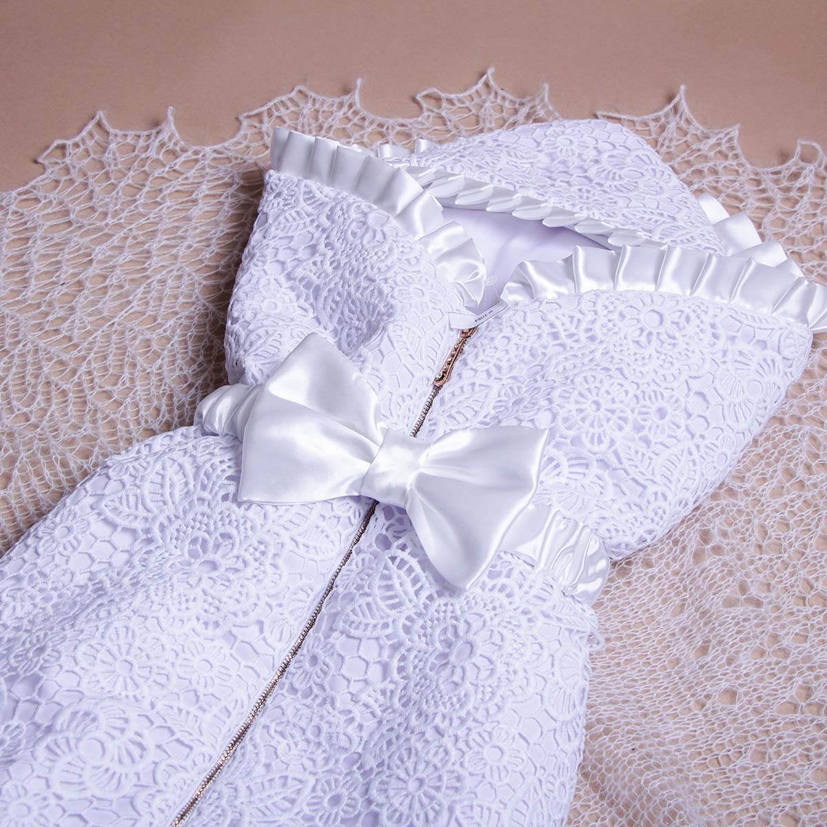 Sleeping sack with hat for summer with a bow and star design on a textured beige background