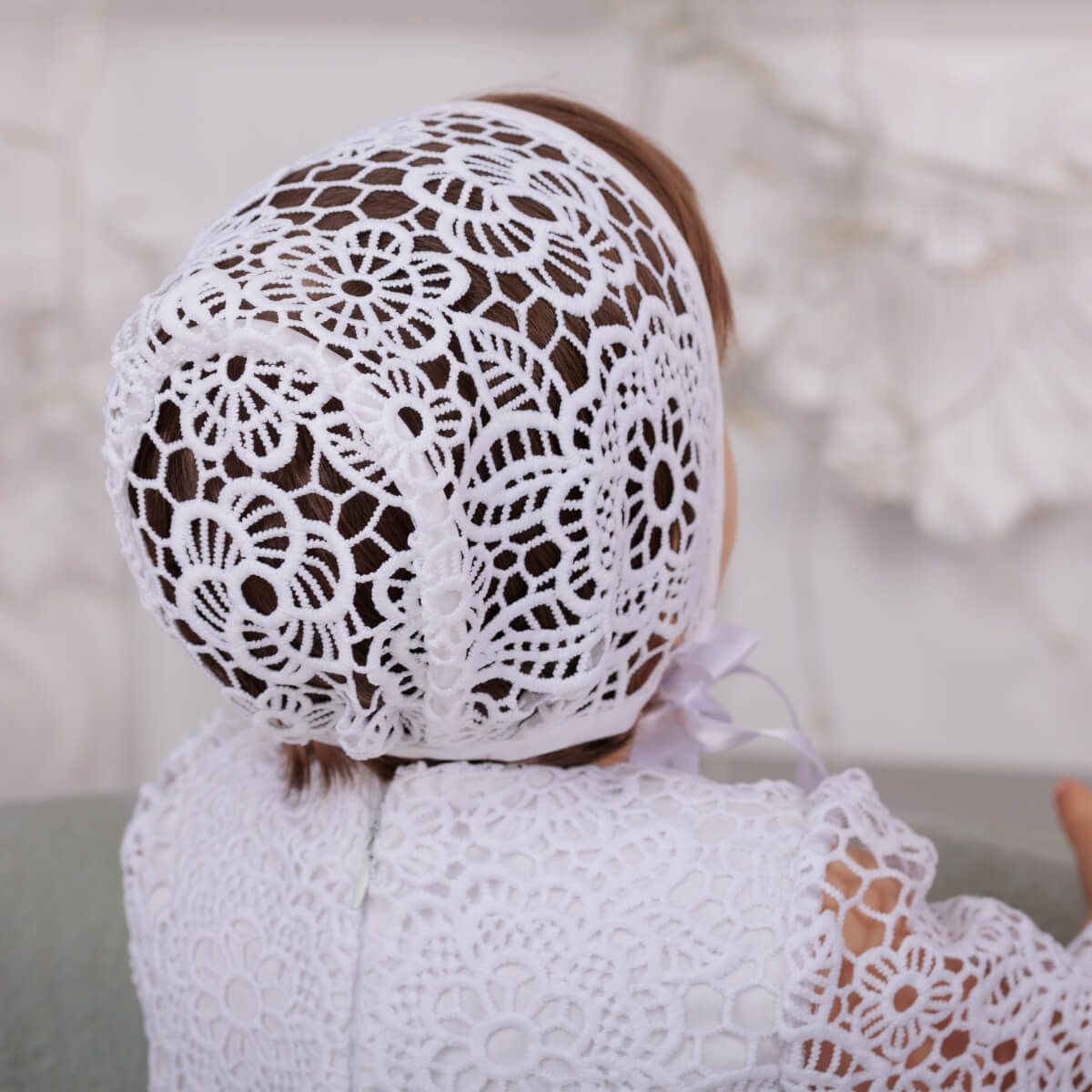 Person wearing a and dLace Baptism Bonnet a background