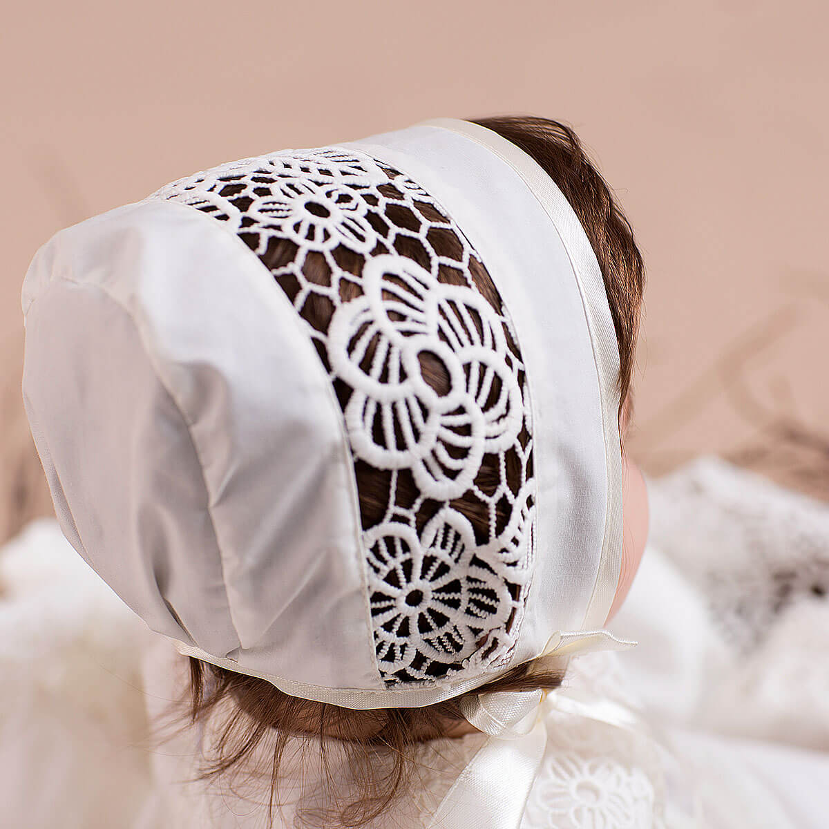 Lace Baptism Bonnet detailing worn by a person on a beige background