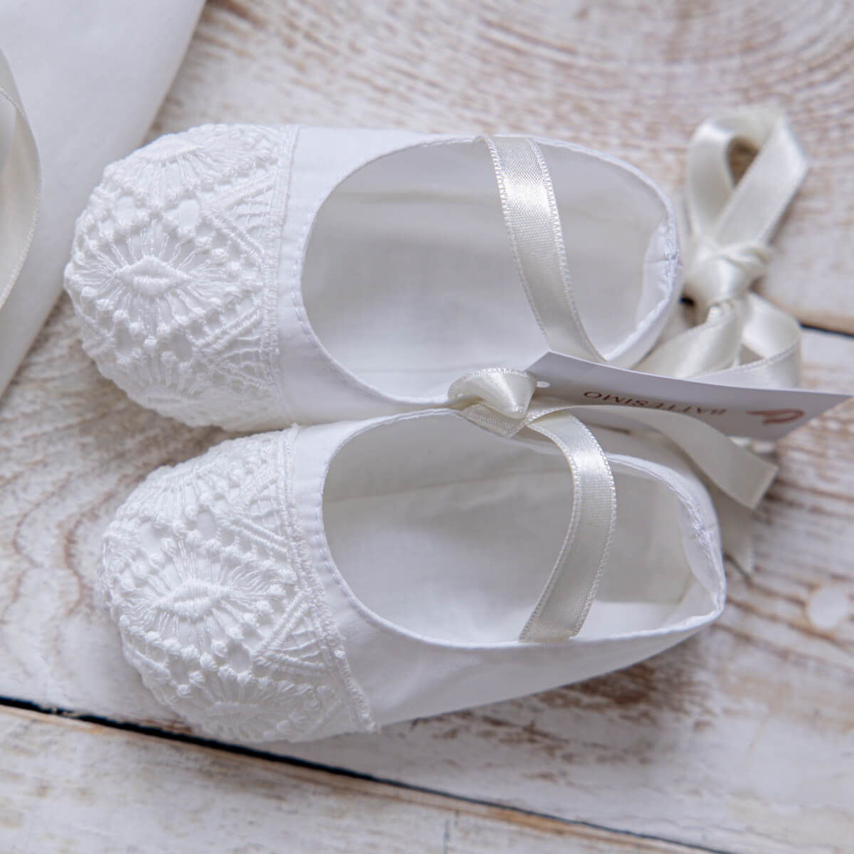 White lace-up shoes with ribbons of Baptism Dress Set for Girl on a wooden surface