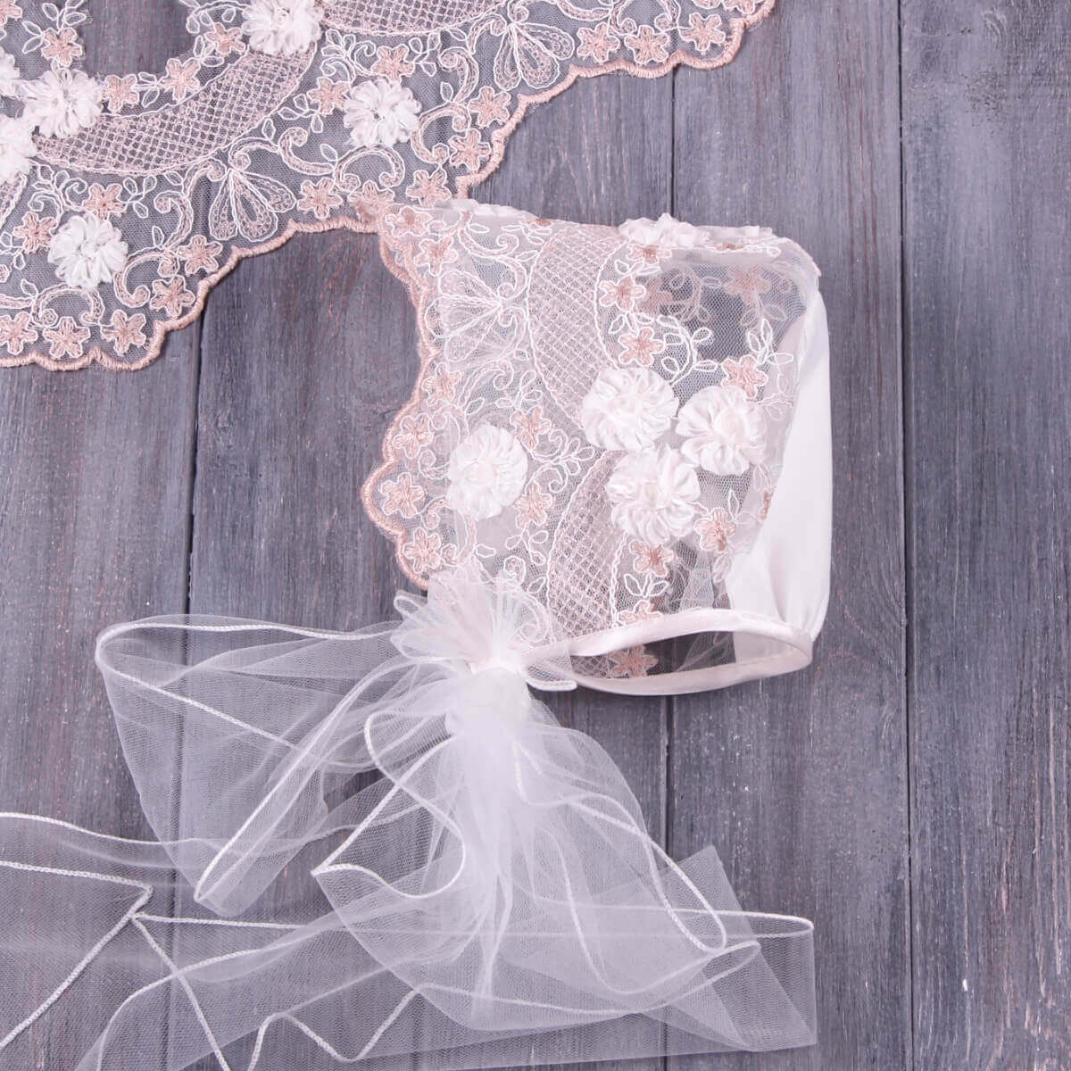 flower lace baptism bonnet with floral embroidery on a wooden background