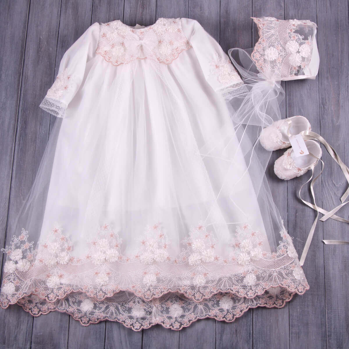 Long Christening Gown for Girls with matching shoes on a wooden surface