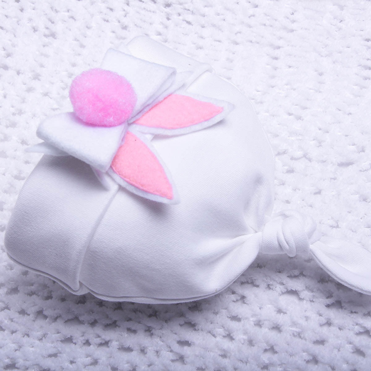 White bunny mask with pink ears and nose on a textured white background