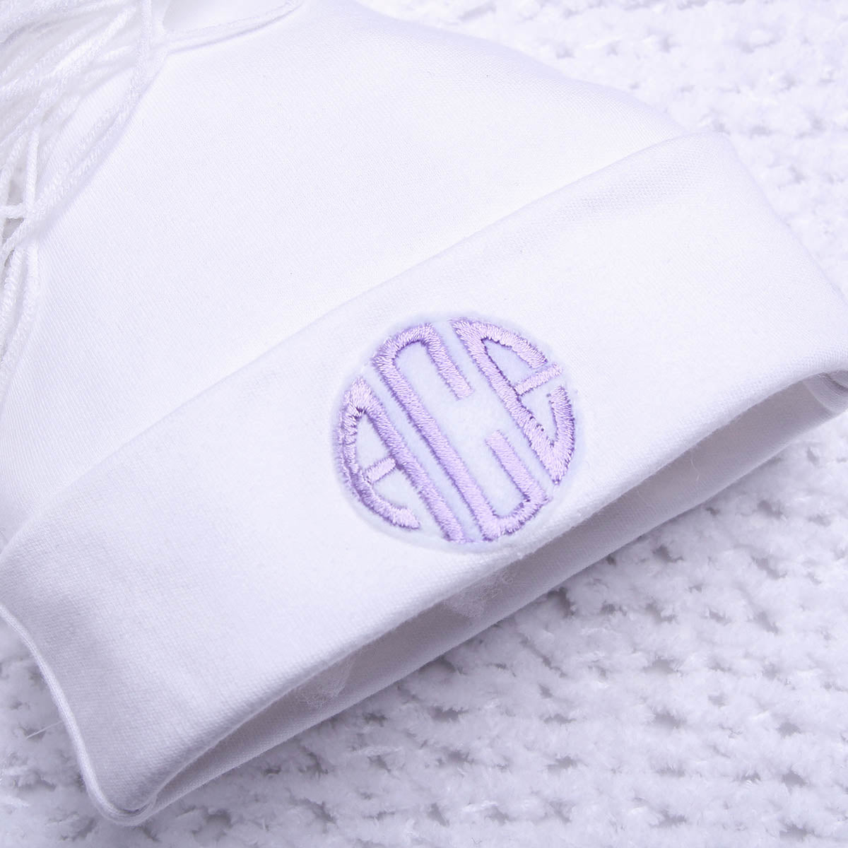 White sweatshirt with a purple embroidered monogram on a marble surface