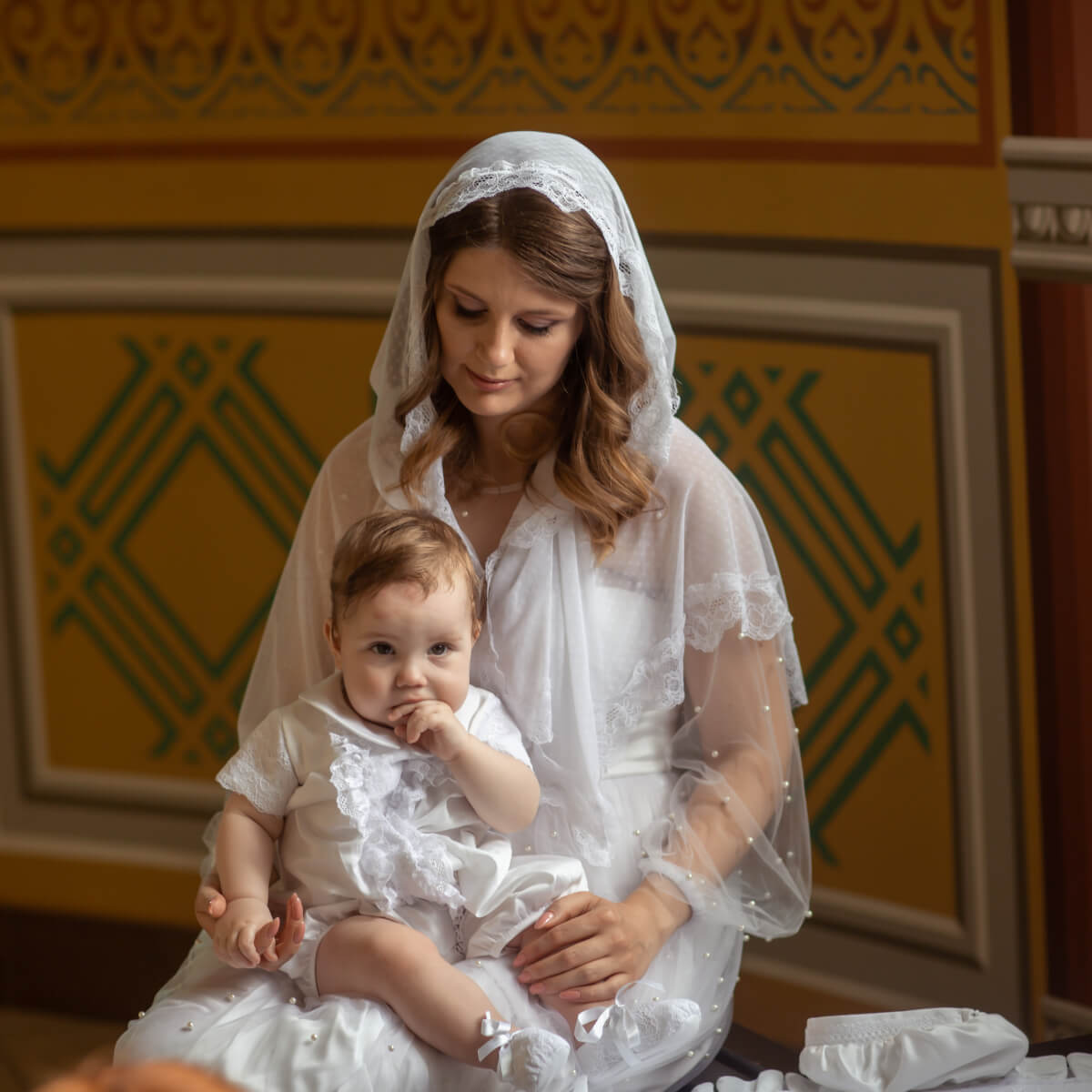 Woman in a Catholic Church Mantilla holding a baby in a decorated room