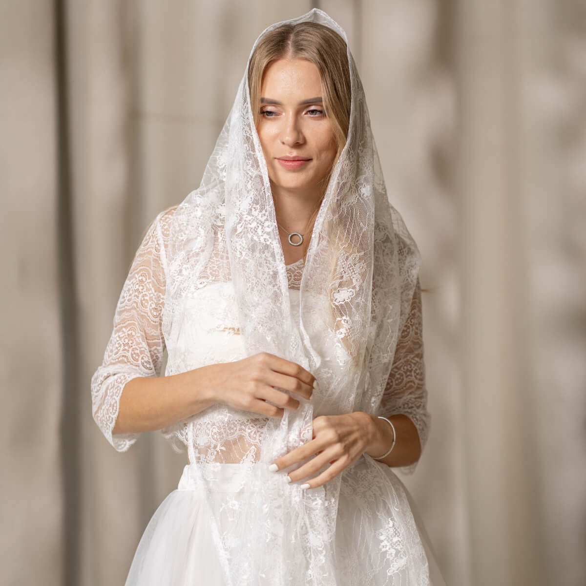 Woman wearing a Lace Chapel Veil against a neutral background