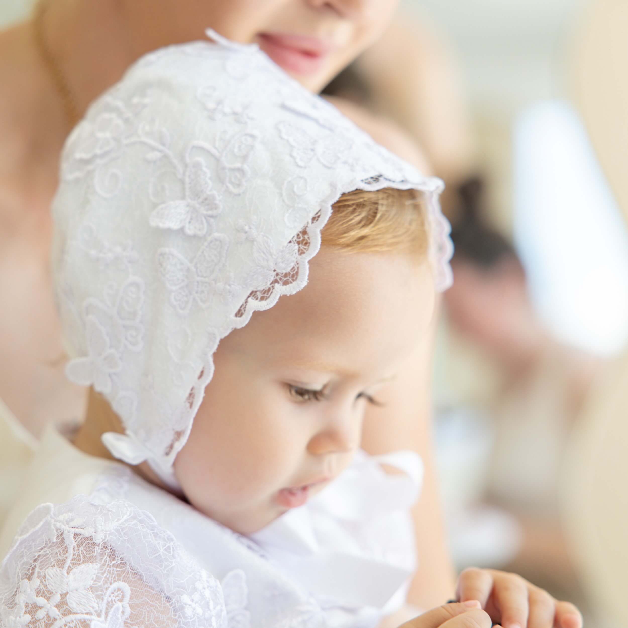 Child wearing a lace baptism bonnet with a blurred background
