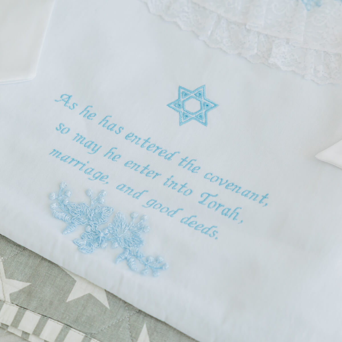 Embroidered text and Star of David on a white fabric background