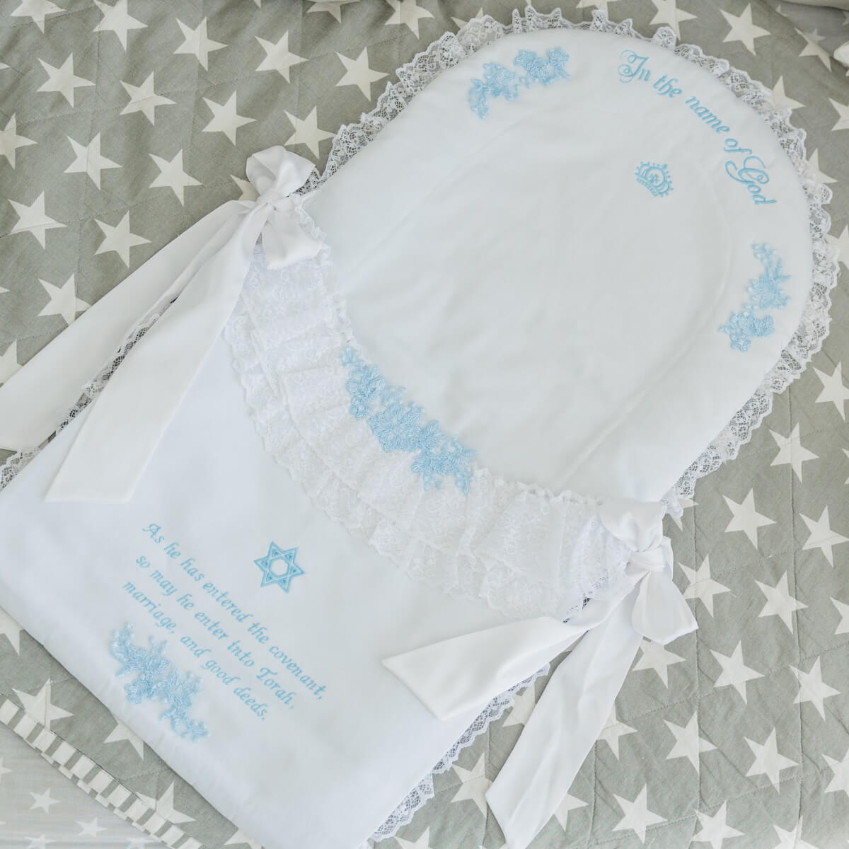 White baby blanket with blue embroidery on a gray blanket with white stars