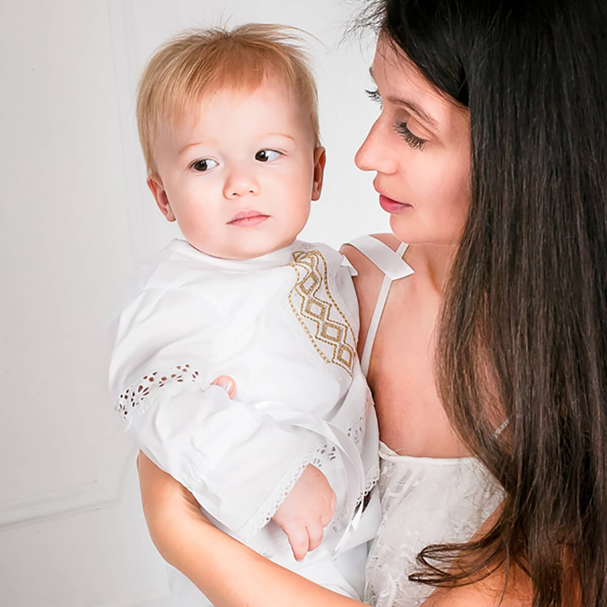 Woman holding a baby wearing a Baby Boy Baptism Suit with gold embroidery against a plain background