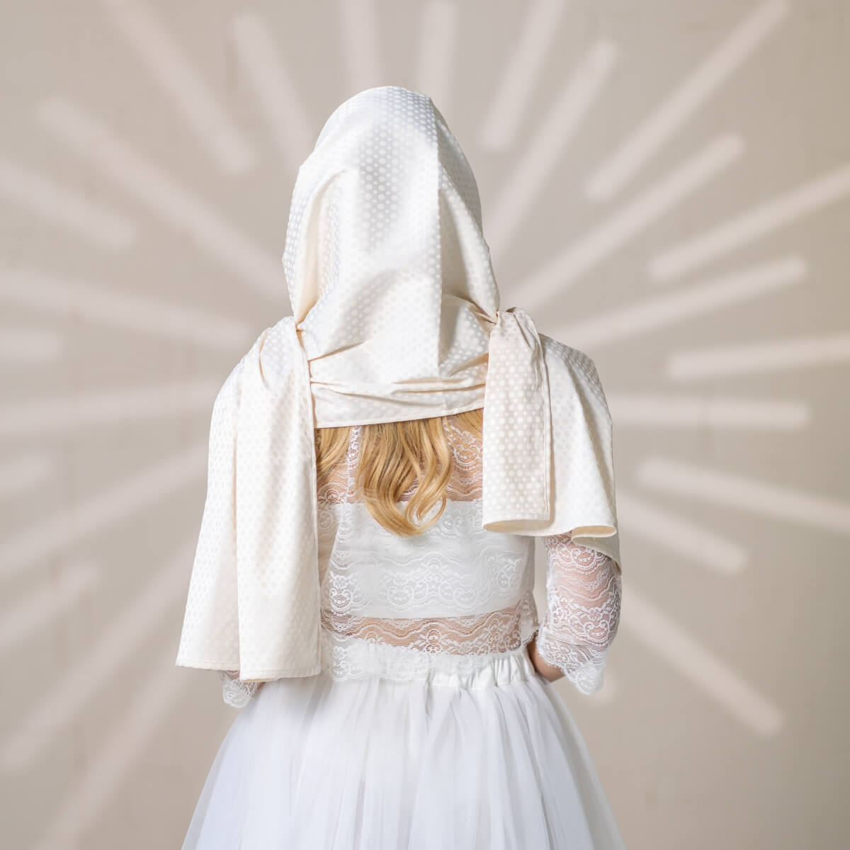 Person wearing a white lace dress with a Silk Chapel Veil on a neutral background