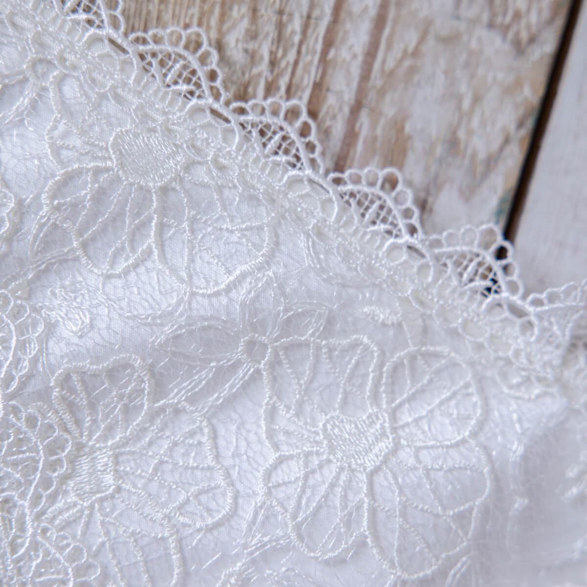 Close-up of white lace fabric with floral patterns on a wooden surface
