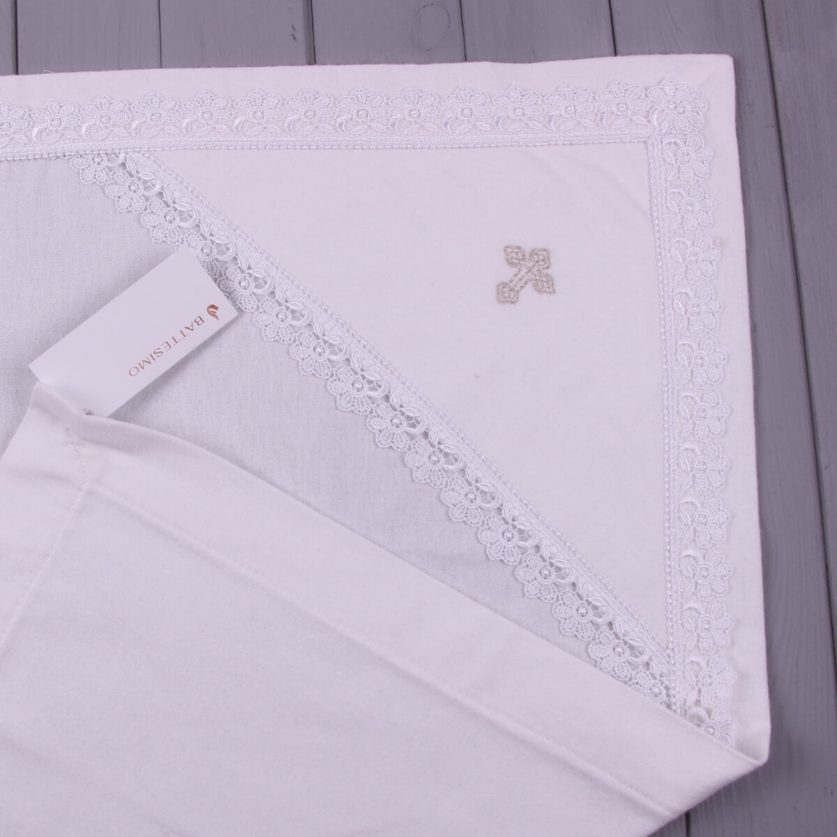 White baptism blanket with a brand tag on a wooden surface