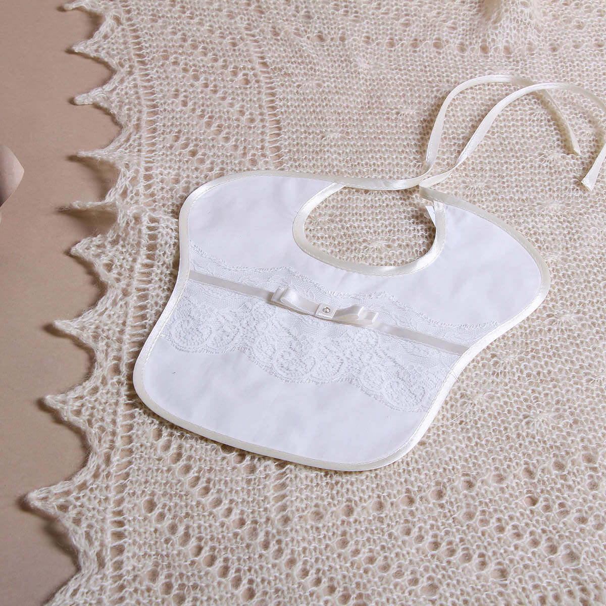 Baptism Bib on a textured beige surface