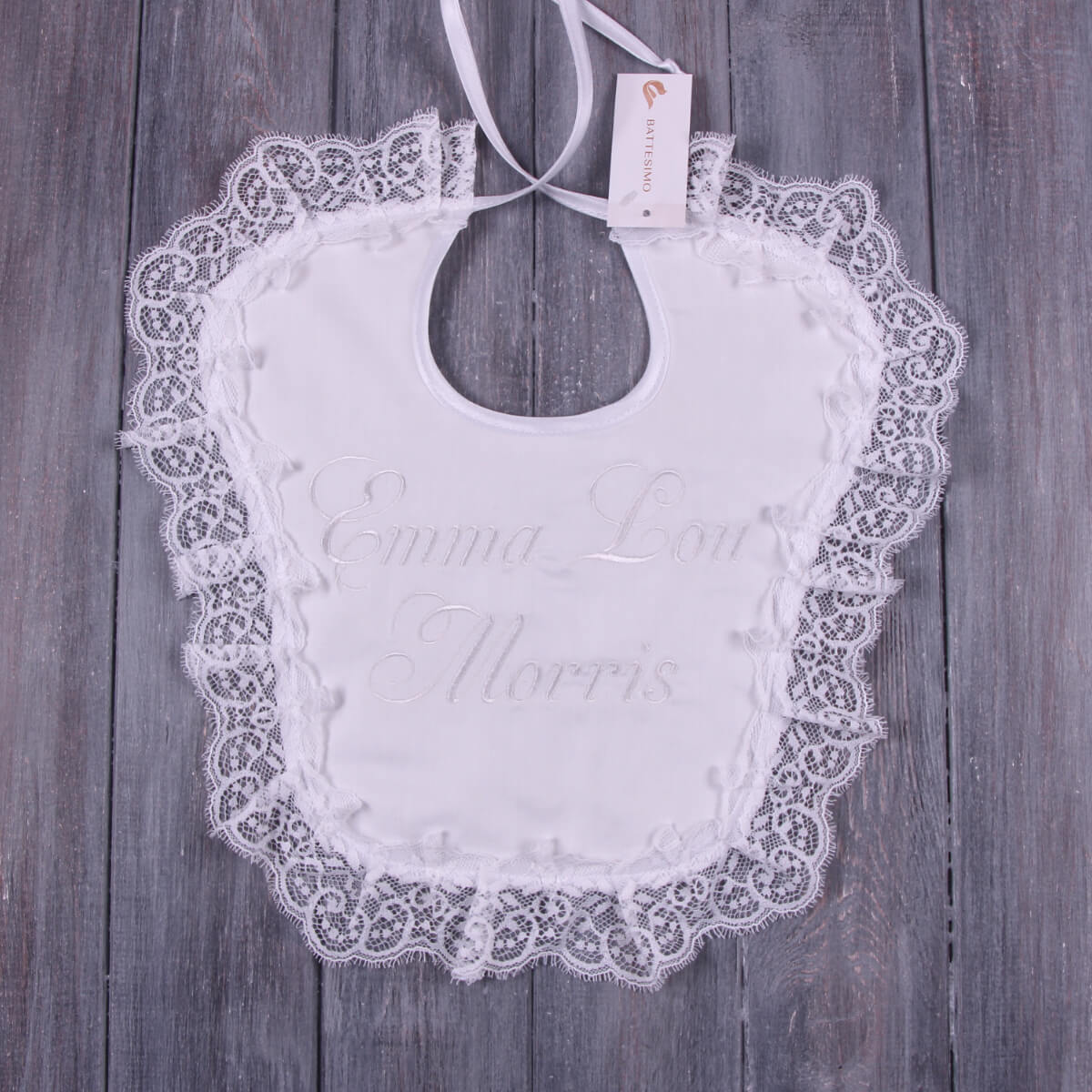 Baptism Bib with embroidered text on a wooden surface