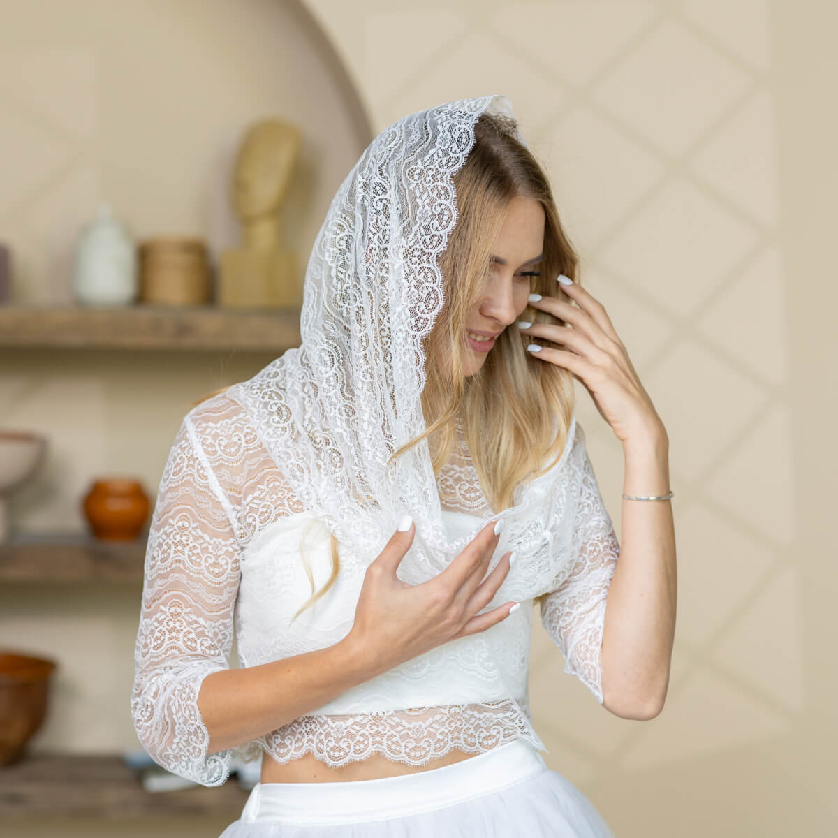 Woman wearing a Catholic Infinity Veil and holding a white bird in a rustic setting.