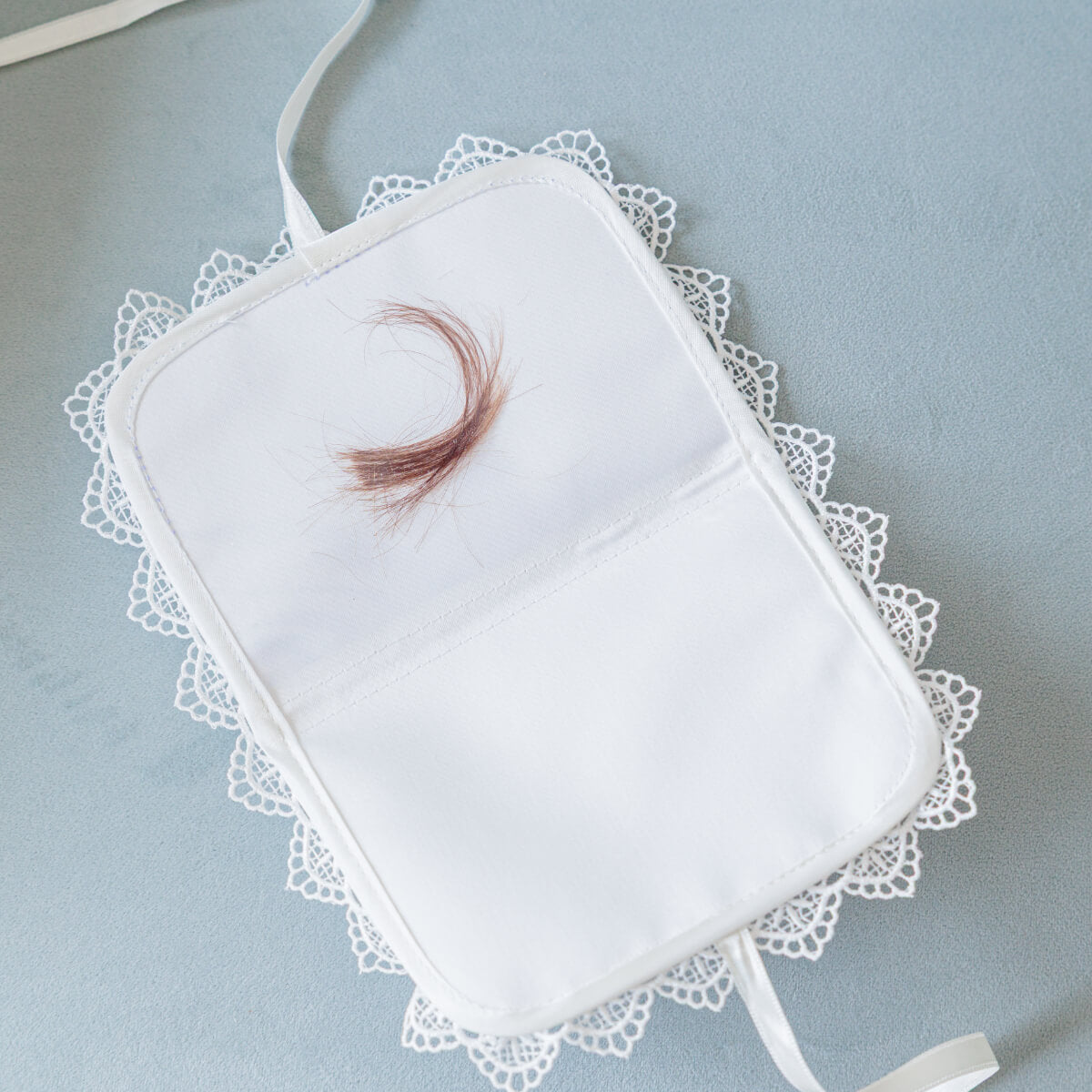 Baptism Keepsake Box for First Curl with a feather on a light blue background