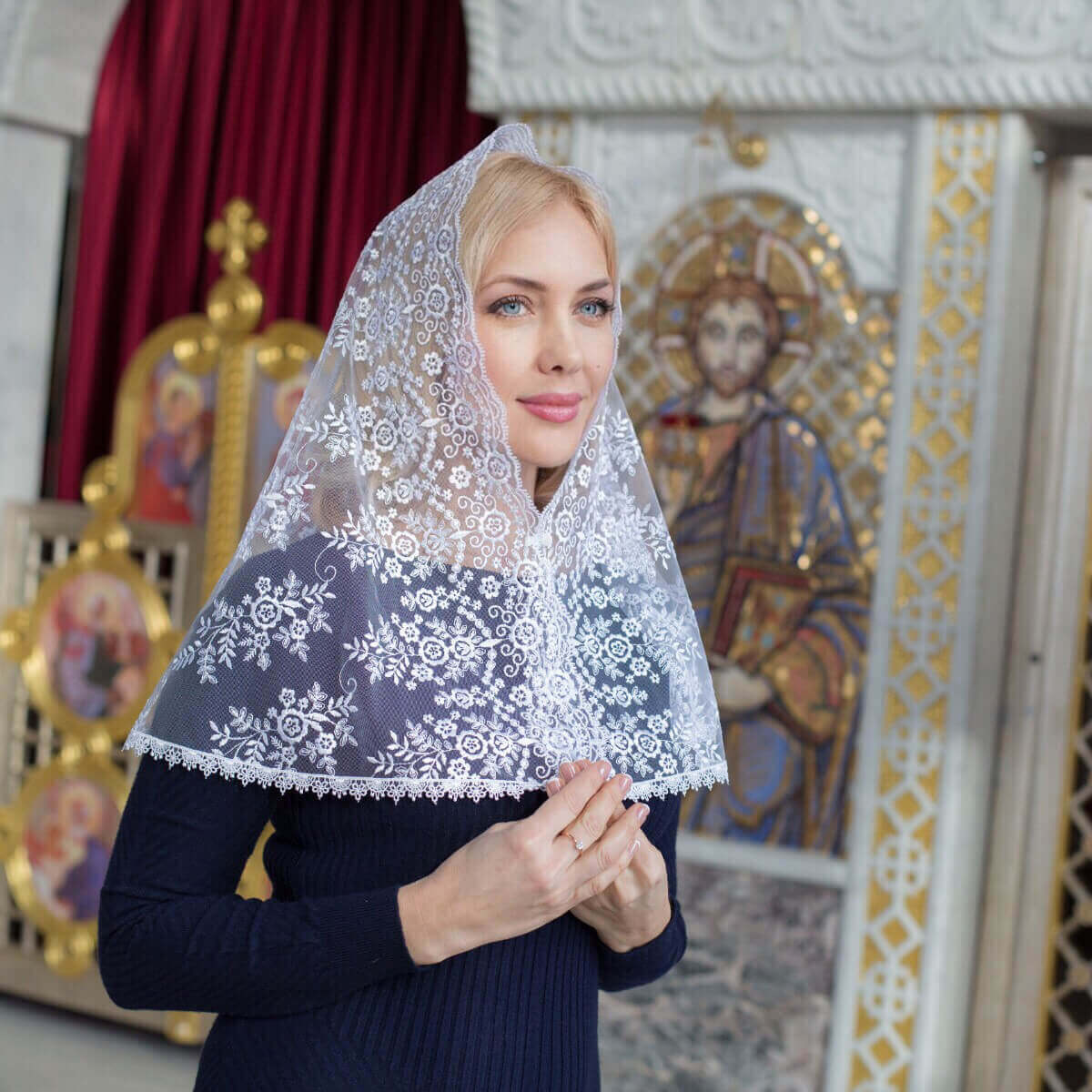 Woman wearing a Catholic Church Mantilla in an ornate interior setting with religious iconography.