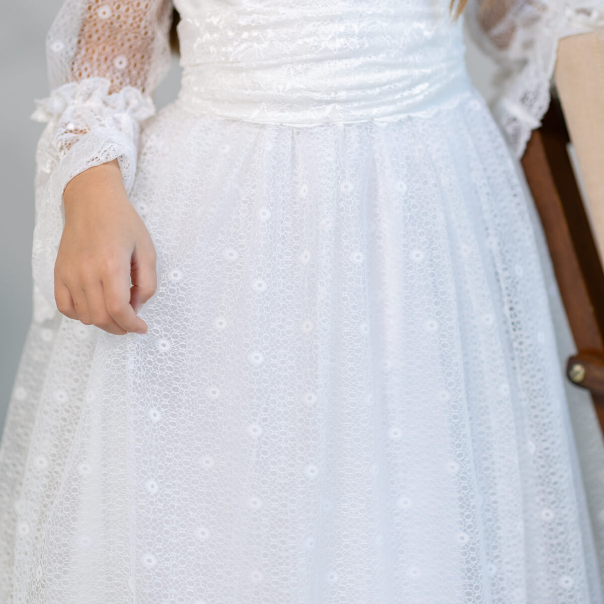 White lace dress with intricate detailing on a neutral background
