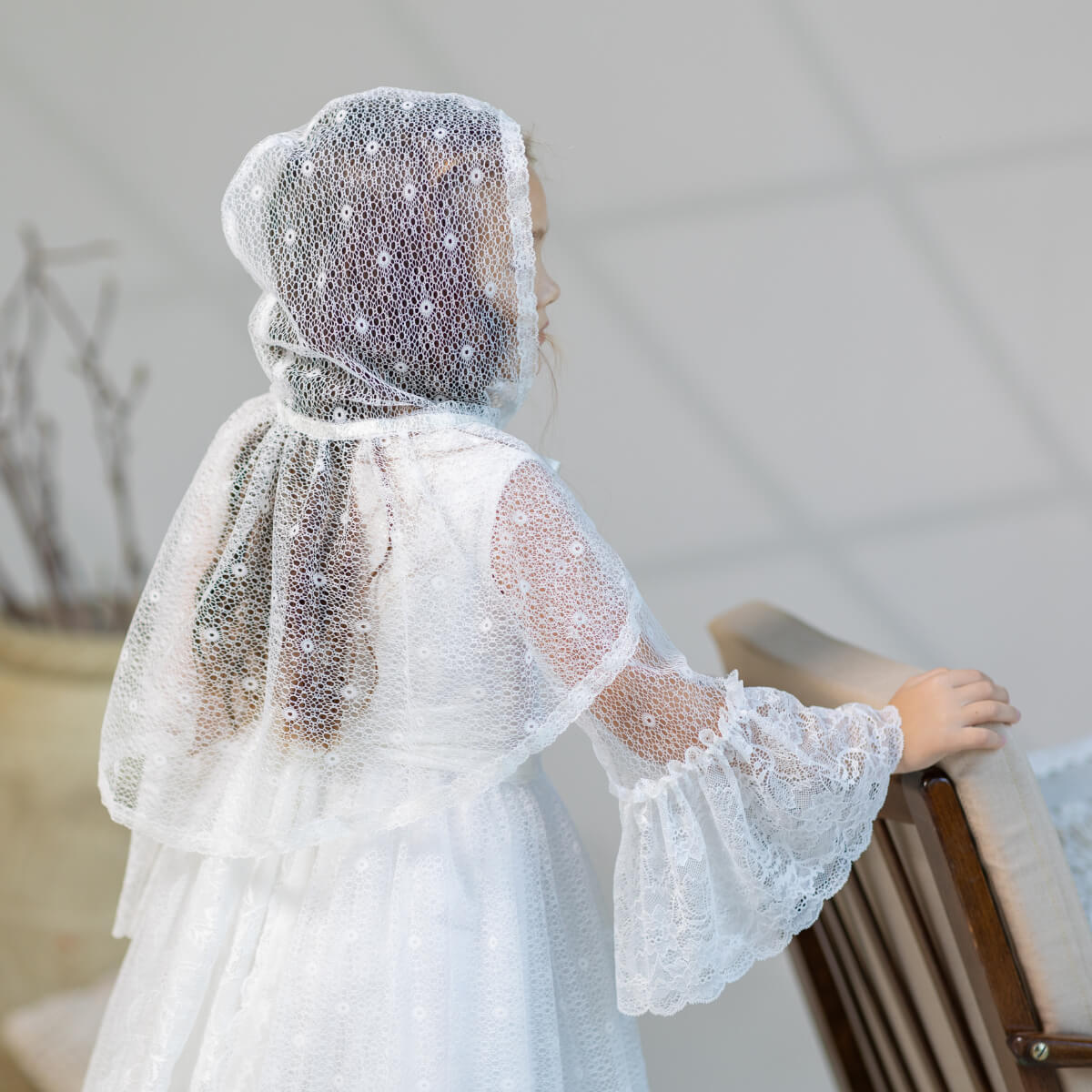Person wearing a Elegant cotton communion dress with a mantilla in a neutral setting