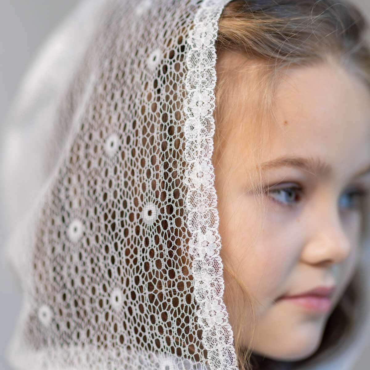 First Communion Mantilla Veil covering worn by a young girl.