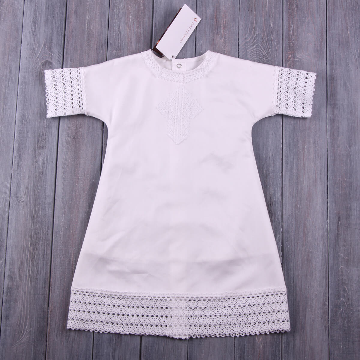 Baptism Gown with lace details on a wooden surface