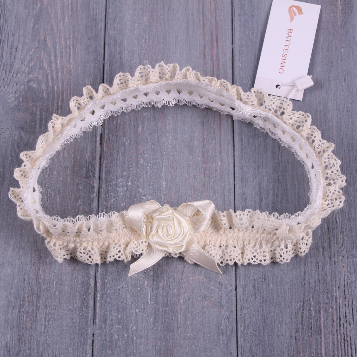 Baby headband with a rose detail on a wooden surface