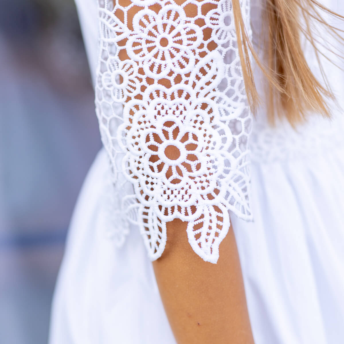 Close-up of a white lace sleeve on a garment with a blurred background