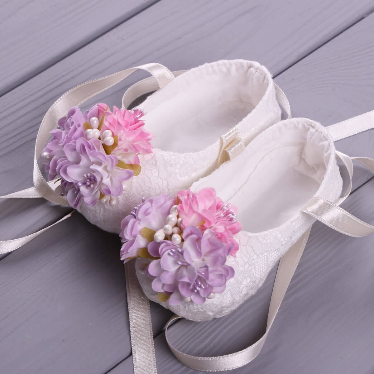 Christening Booties with floral decorations on a wooden surface