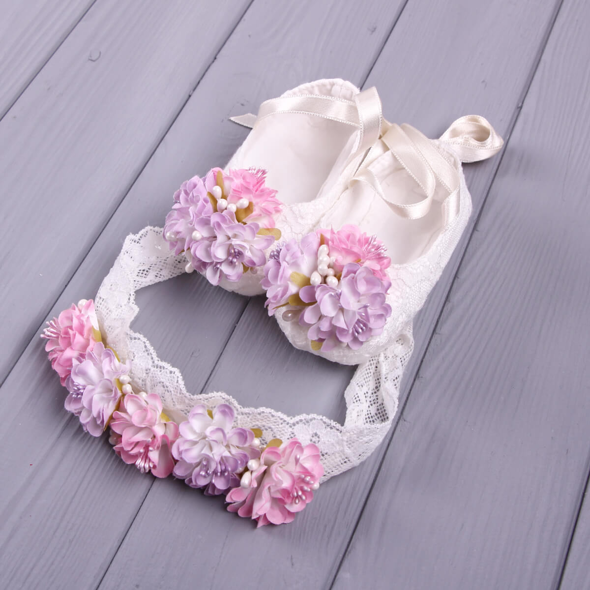 Christening Booties with pink floral decorations on a wooden surface