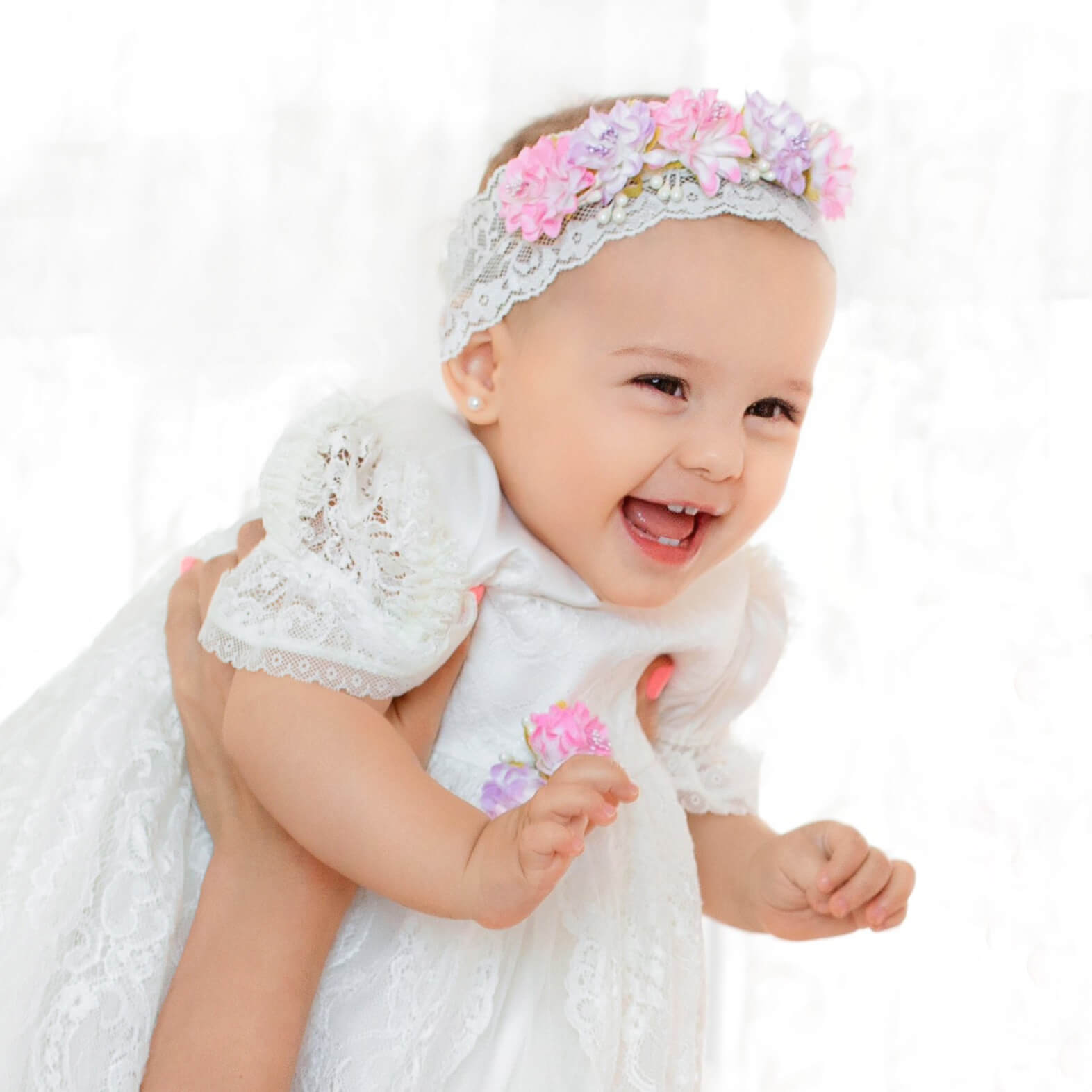 Baby in a white outfit with baby headband on a white background