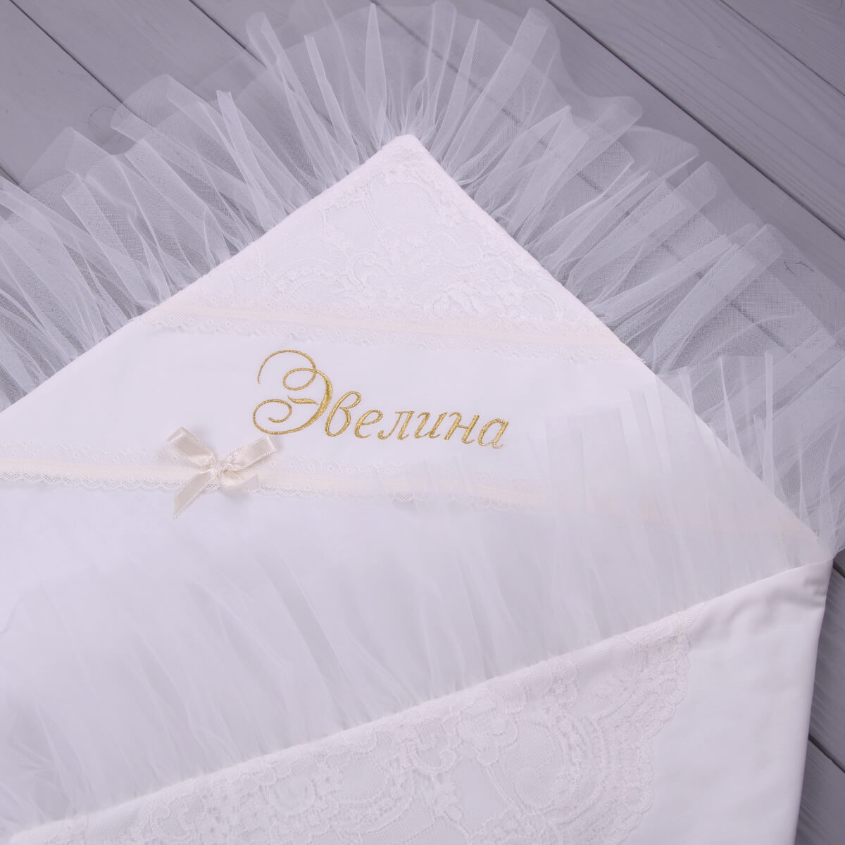 White christening blanket with embroidered name on a textured surface