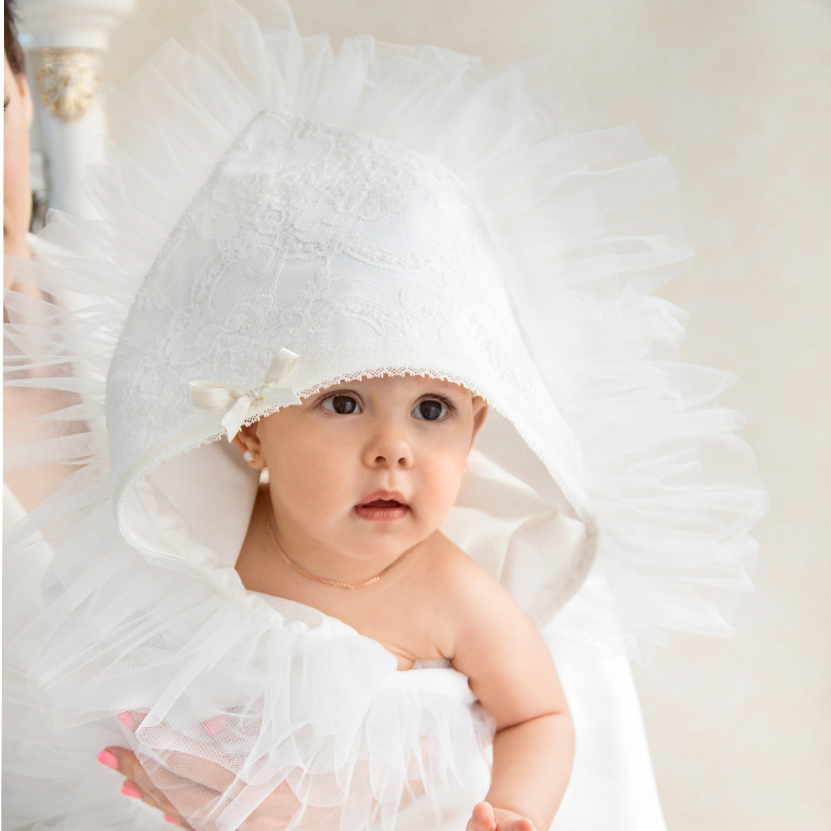 Baby wearing a white ruffled outfit with a matching headband.
