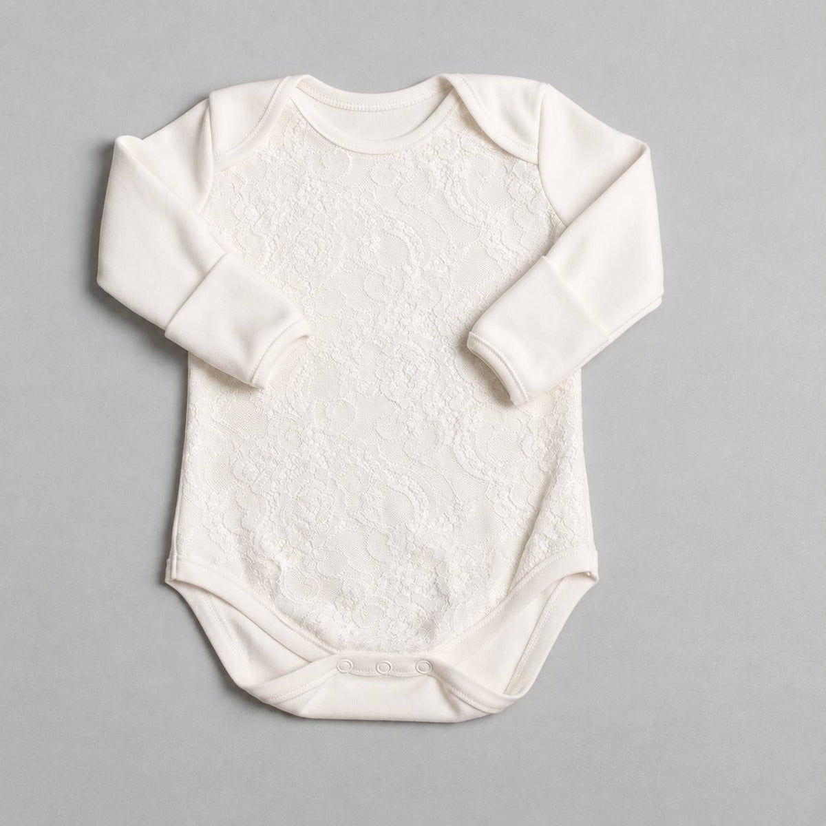 An off-white long-sleeve baby bodysuit with a textured lace-like pattern across the chest, laid flat on a neutral gray background.