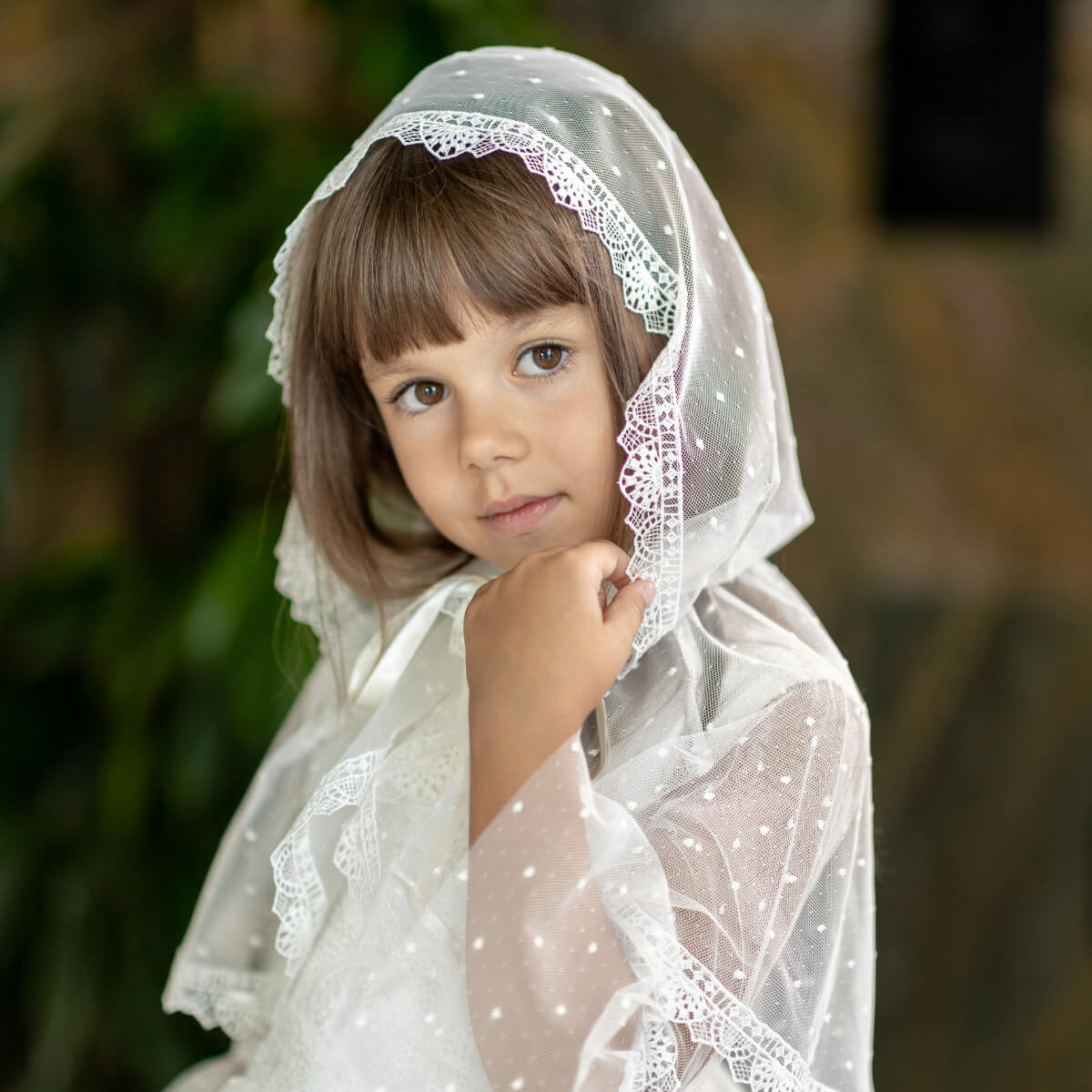 Young girl wearing a First Communion Veil against a blurred natural background