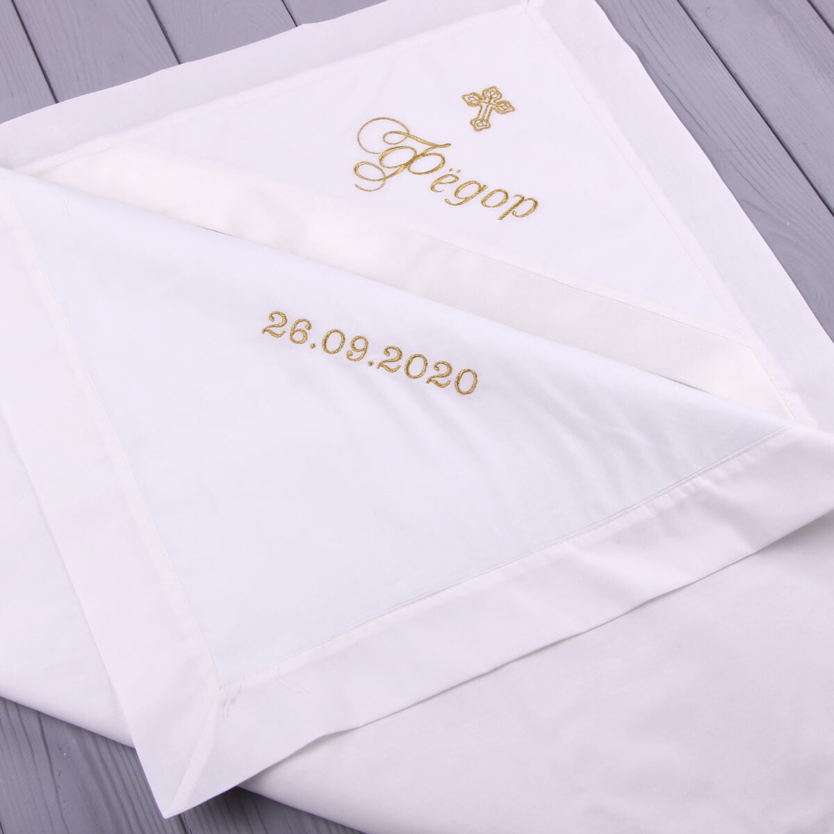 Baptism Blanket with gold embroidery on a wooden surface