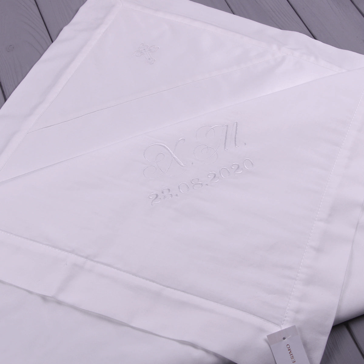 Baptism blanket with a brand logo and text on a gray wooden surface