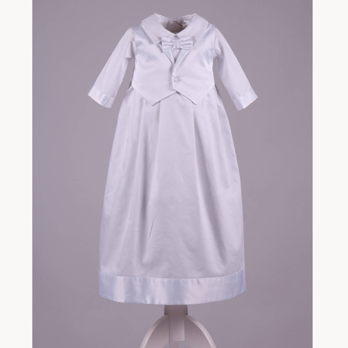 White baptism christening gown with a bow on a gray background