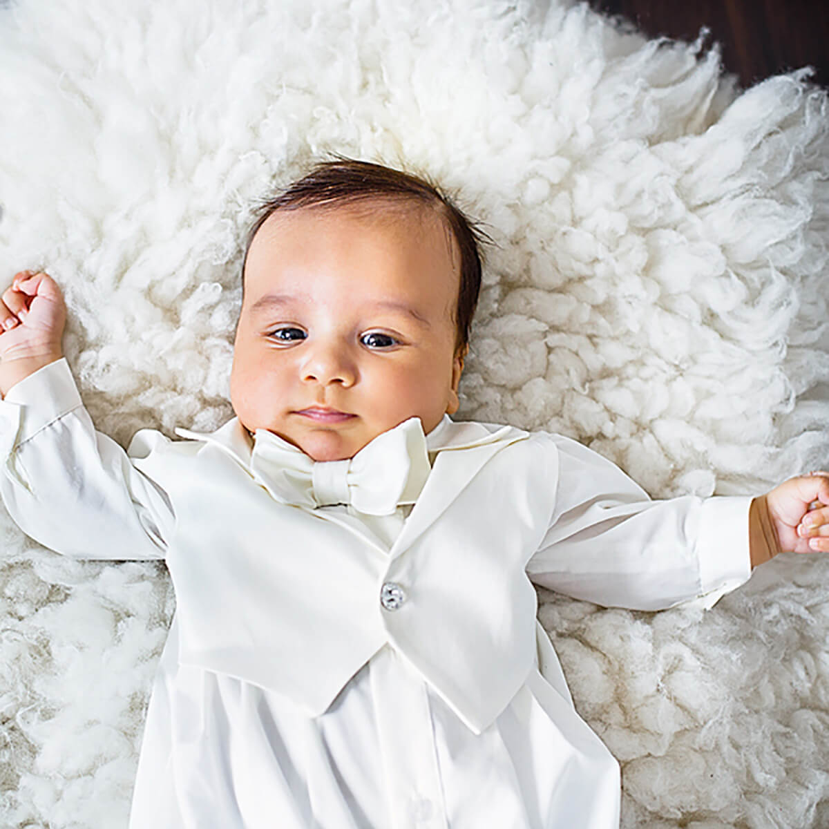 Baby in a Baby Boy Baptism Romper lying on a fluffy white rug