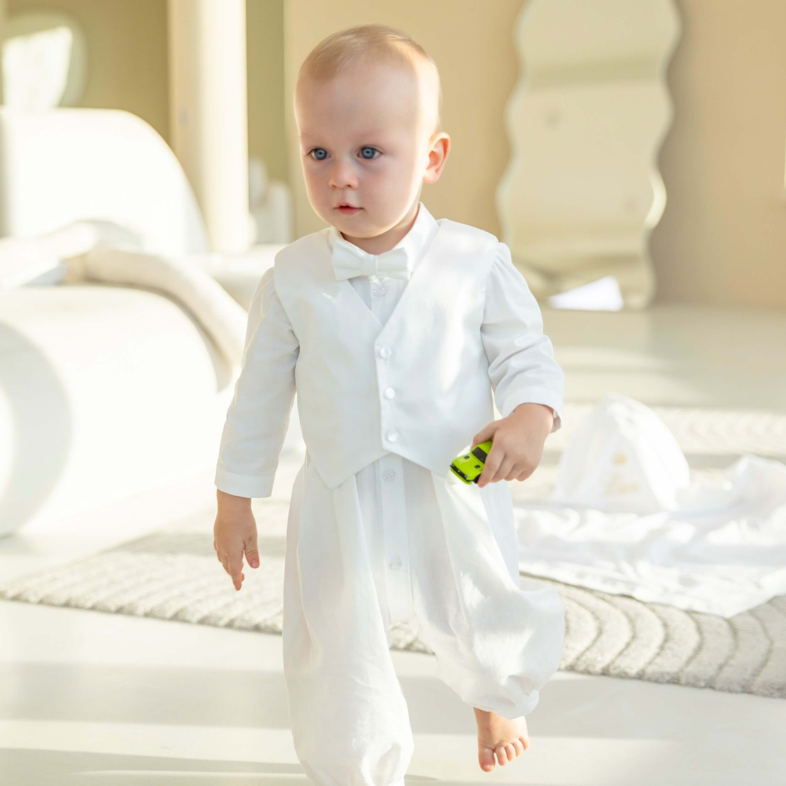 Baby in a Baby Boy Baptism Romper standing on a bed