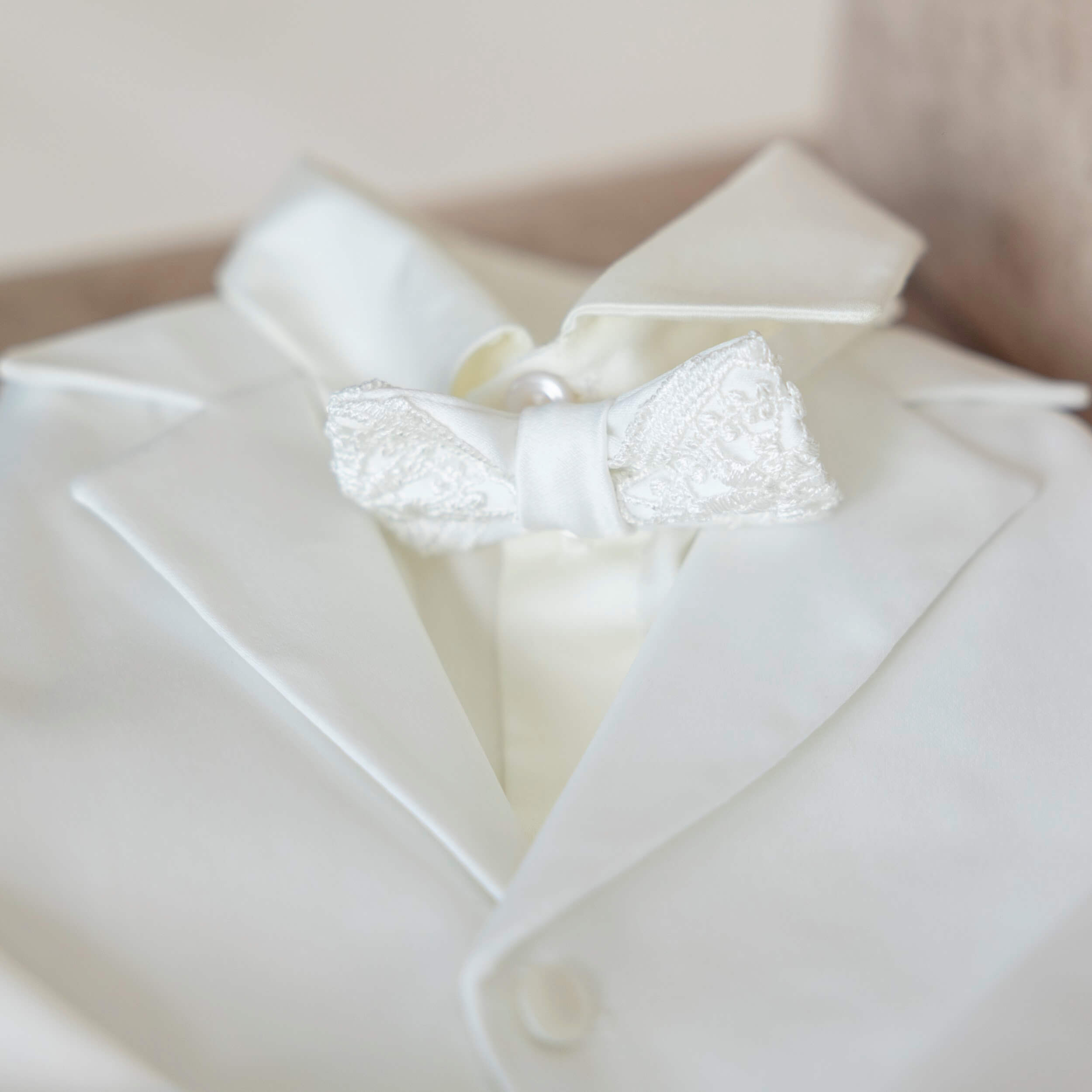 Baptism Suit for Baby Boys with a lace bow tie on a neutral background