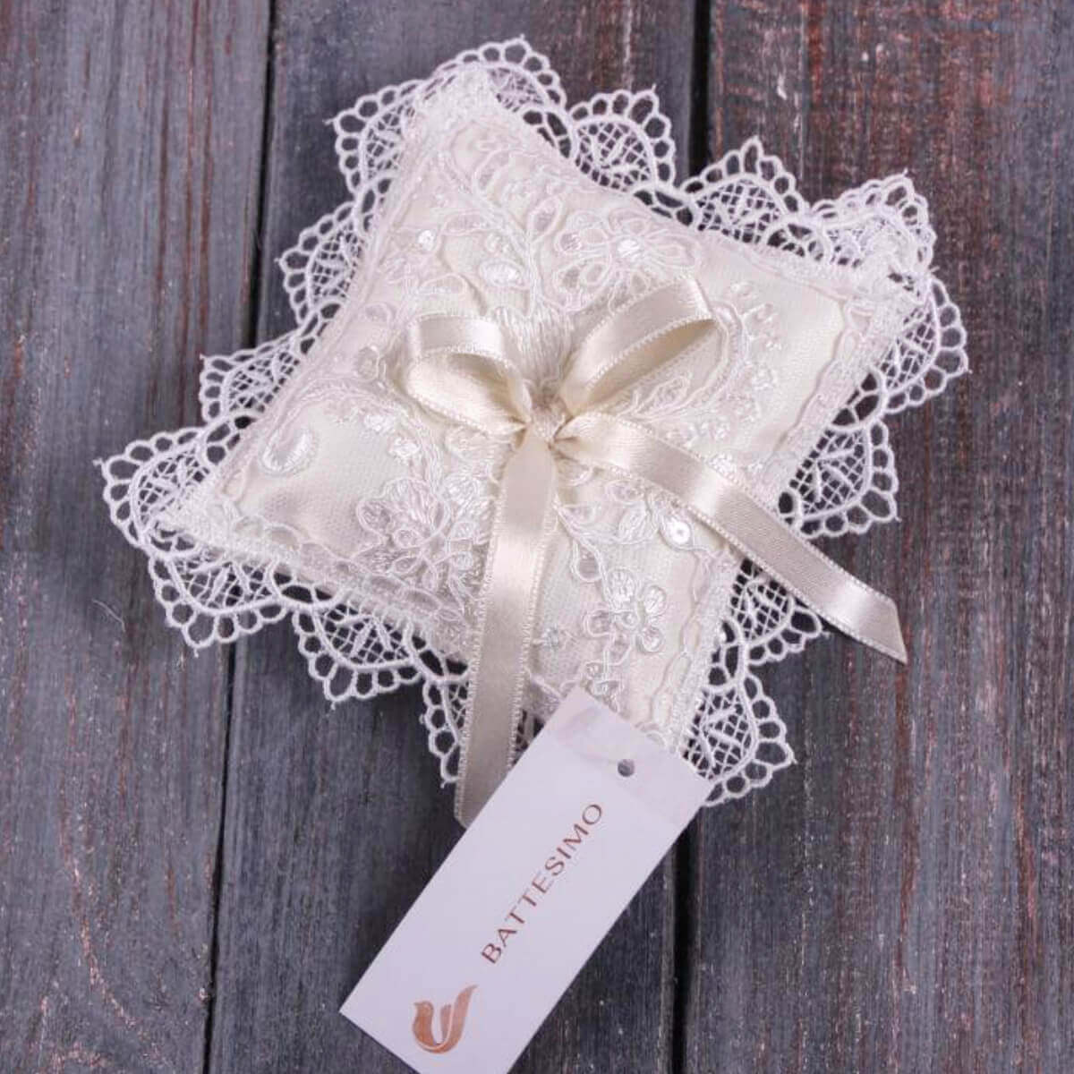 Baptism Ceremony Pillow with a bow on a wooden surface, featuring a 'Battesimo' tag.