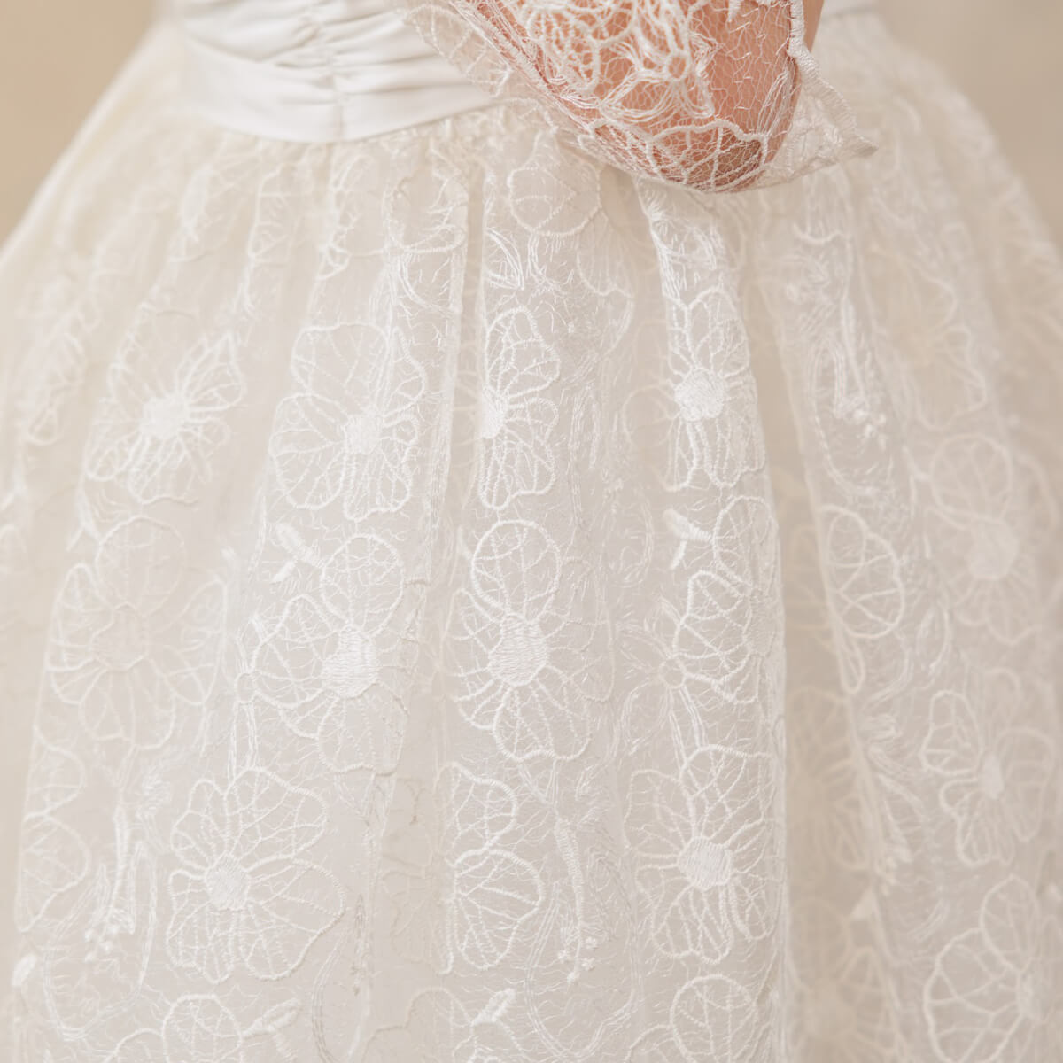 Close-up of a white lace First Communion Dress with intricate patterns.
